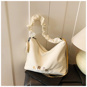 Détail du sac cabas plissé crème avec broderie et une pochette ronde assortie en pendentif