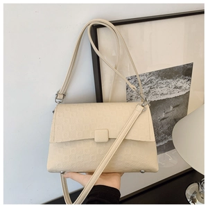 Detail of cream PU leather crossbody bag showing geometric embossed texture and silver studs