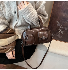 Close-up of vintage brown gloss handbag featuring functional front pockets and metallic hardware