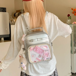Sac à dos Ita argenté avec fenêtre transparente et lapin en peluche dans un café