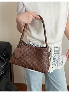 Dark brown woven tote bag with shoulder strap and matching charm accessory