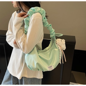 Close-up of mint green dumpling bag with cloud pleats and fluffy white pendant