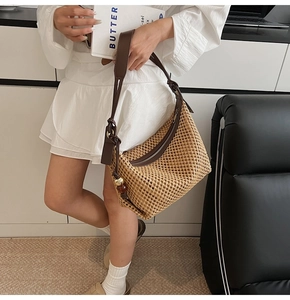 Détail du sac à bandoulière tressé bohème avec sangle en cuir et pendentif perle en bois
