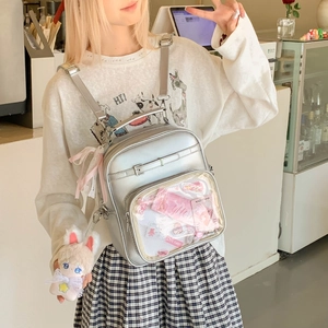 Détail du sac Ita argenté avec fenêtre PVC et porte-clé lapin dans un décor de café