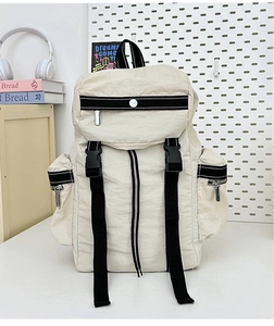 Detail view of large cream travel backpack with wide black straps and side zipper pockets