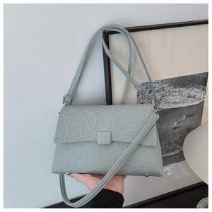 Detail of light blue crossbody bag featuring embossed square pattern and bottom metal studs