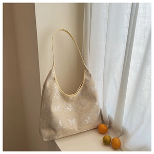 Close-up of beige tote bag featuring elegant butterfly embroidery and vintage textures