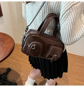 Detail of dark brown glossy crossbody bag featuring silver buckles and functional pockets