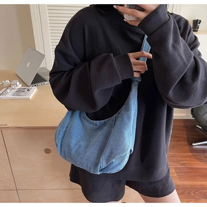 Lifestyle shot of a spacious light blue denim crescent shoulder bag with wide strap
