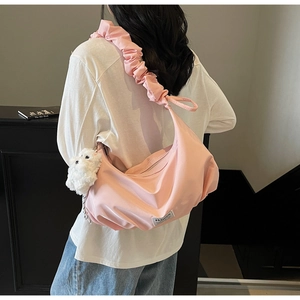 Pink nylon shoulder bag with ruffled strap and plush dog charm shown on a model