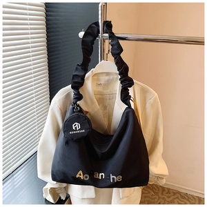 Détail de la bandoulière plissée noire et de la broderie sur le grand sac cabas