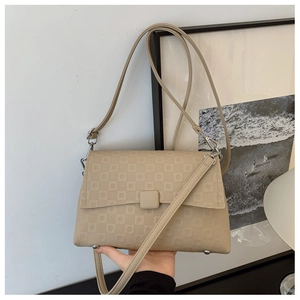 Close-up of beige shoulder bag with geometric embossed pattern and silver hardware