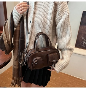Detail view of dark coffee faux leather pillow bag with double handles and front pockets