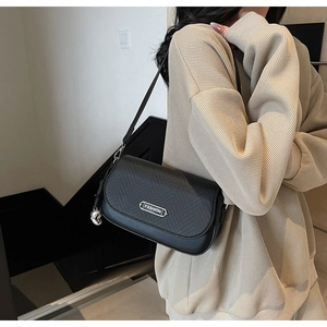 Détail de la texture tissée noire sur le rabat avec plaque FASHION argentée