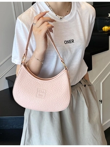 Pink pebbled leather baguette bag with gold hardware and curved shoulder strap design