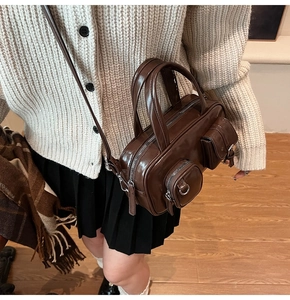 Street style shot of a dark brown retro crossbody bag with dual silver front zippers