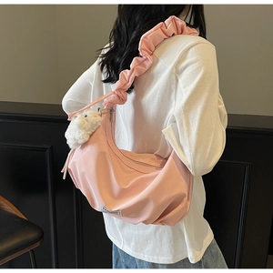 Detailed shot of a pink crescent bag with a ruched cloud strap and cute rabbit pendant