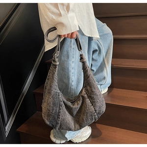Detail of hobo bag showing acid wash denim fabric and knotted shoulder strap detail
