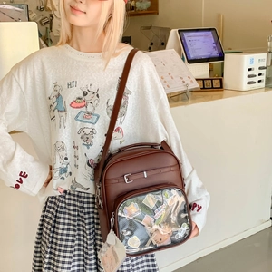 Détail du sac Ita marron foncé avec poche transparente montrant des accessoires en peluche