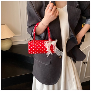 Close-up of red polka dot cylinder handbag with lace bow and pearl chain detail