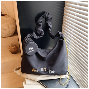 Détail du sac cabas noir avec bandoulière à volants et petit porte-monnaie accroché