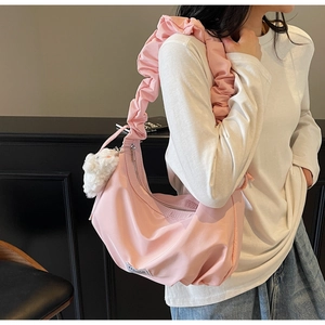Detailed view of pink nylon crescent bag featuring cloud pleated strap and plush ball