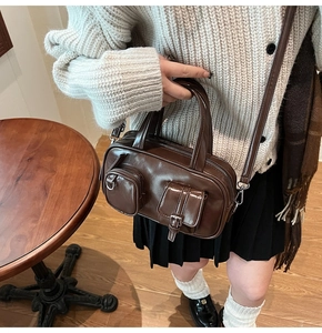 Brown vintage faux leather crossbody bag with utility pockets and top handle shown on a table