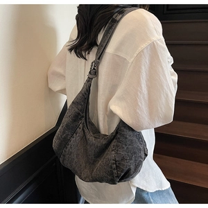 Close-up of a dark grey oversized hobo bag showing its washed denim texture and wide strap
