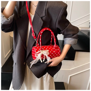 Red cylindrical polka dot handbag with pearl lace bow detail shown on models outfit