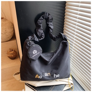 Détail du sac cabas noir avec bandoulière à volants et petit porte-monnaie rond amovible