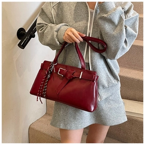 Detail of burgundy shoulder bag with leather belt buckle and woven rope ornament