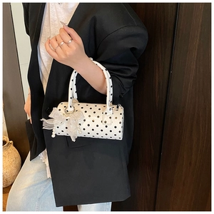 Vue détaillée du sac cylindrique à pois avec nœud en dentelle blanche et bijou de perle