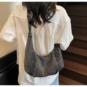 Detail of adjustable strap and washed denim texture on a gray hobo shoulder bag