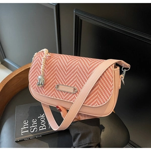 Détail du sac bandoulière rose avec rabat à chevrons tissé et plaque logo argentée
