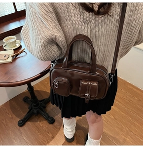 Detail of vintage brown Boston bag with front pockets and metallic hardware in cafe setting