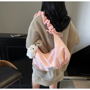Detail view of pink dumpling shoulder bag with ruched strap and cute plush bear charm