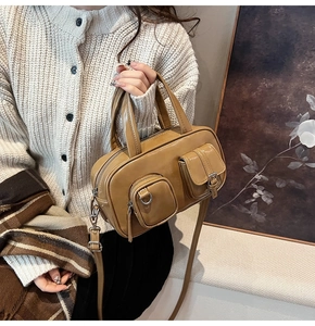 Detail view of khaki retro boston bag showing the ring zipper and buckle front pockets