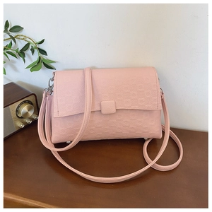 Close-up of pink embossed leather shoulder bag with floral patterns on a wooden surface
