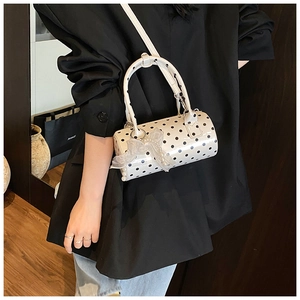Detailed view of white polka dot barrel bag featuring lace bow and pearl pendant charm