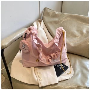 Détail du sac cabas plissé rose avec son petit pendentif rond sur un blazer beige