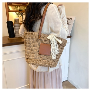 Detail of woven straw tote bag with brown leather straps and white lace bow accessory
