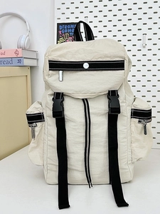 Waterproof cream travel backpack with black straps and buckle closure in room setting