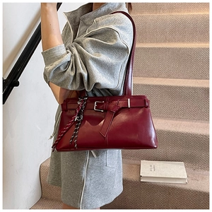 Detail of vintage burgundy shoulder bag featuring shiny leather and metal buckle adjustment
