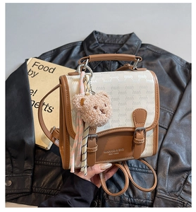 Détail d'un sac à main carré étanche vintage avec motif monogramme et breloque ours