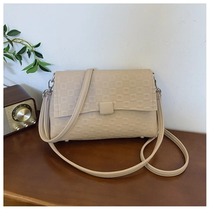 Detail of beige shoulder bag with embossed grid texture and silver bottom feet studs