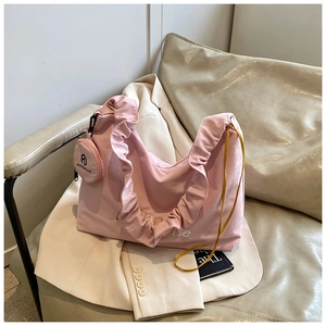 Détail du sac à bandoulière rose plissé avec volants et petit porte-monnaie rond attaché
