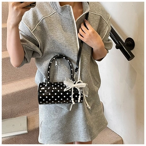 Close-up of black polka dot cylinder bag featuring mesh bow and pearl chain detail