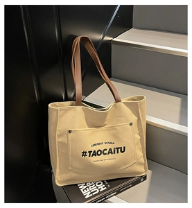 Detail of beige canvas tote bag with brown leather handles on a minimal staircase