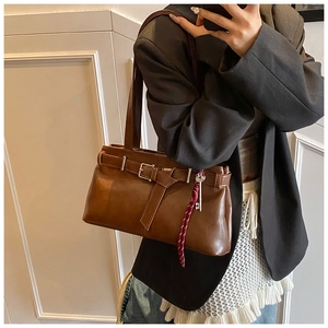 Detail view of retro brown shoulder bag with buckle strap and silver key pendant charm
