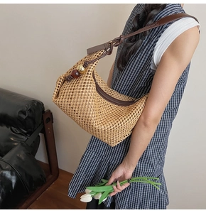 Détail du sac cabas en paille tressée avec bandoulière en cuir et perles décoratives